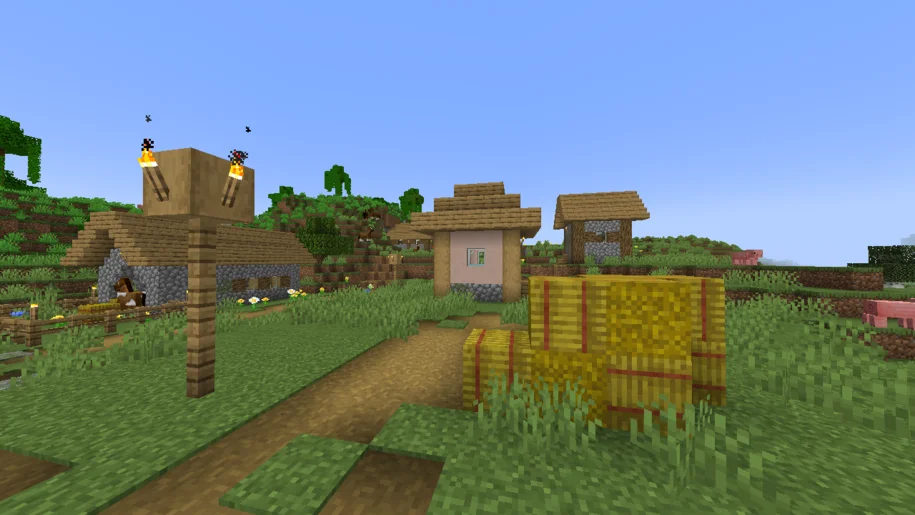Minecraft village with a pile of hay bales in the foreground